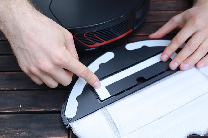 Палец указывает на двигатель, обеспечивающий вибрационные движения моющей пластины Roborock S7 MaxV. 